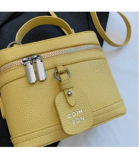 Détail du sac boîte jaune en cuir grainé avec fermetures éclair argentées et anse