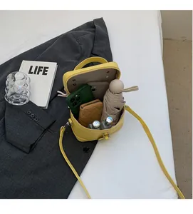 Vue intérieure du sac boîte en cuir jaune montrant l'espace pour téléphone et objets