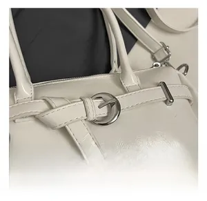 Close-up of white leather handbag with elegant silver circular metal hardware buckle
