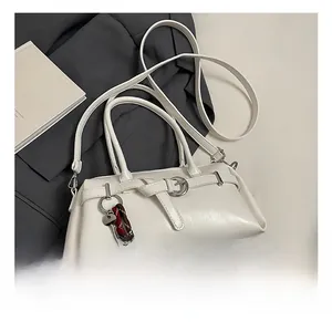 Macro shot of white leather handbag with belt buckle detail and decorative key pendant