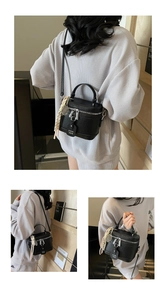 Détail du sac cylindrique en cuir noir avec zips argentés et bandoulière réglable