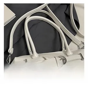 Detail of white handbag with dual handles, silver ring buckle and woven tassel charm
