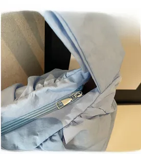 Detail of a smooth silver metal zipper on a light blue ruched cloud shoulder tote bag
