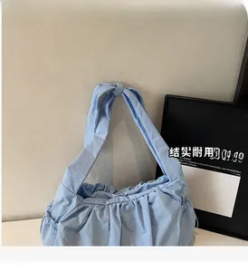 Detail of light blue pleated tote bag showing the unique knotted handle and nylon texture