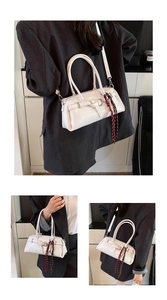 Detail of off-white glossy baguette bag featuring a belt buckle and striped silk scarf