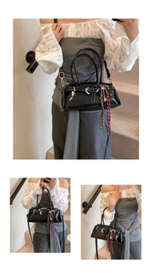 Detail of black glossy handbag featuring silver ring buckle and key-shaped pendant decor