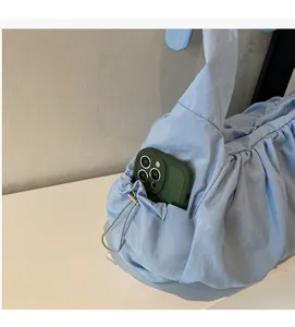 Detail of light blue pleated nylon tote bag featuring a functional outer side pocket for phones