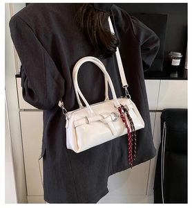 Back view of a model carrying a white leather baguette bag with braided rope charms