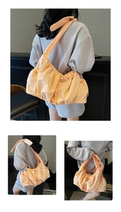 Detail view of the wide knotted shoulder strap on a pleated peach orange tote bag