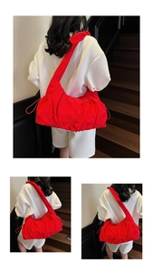 Detail view of a large red ruched hobo bag featuring cloud pleats and wide shoulder strap