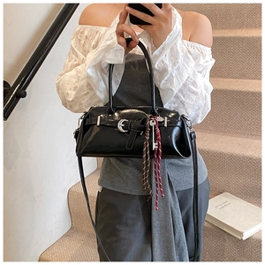 Detail of black glossy patent leather shoulder bag with belt trim and silver buckles