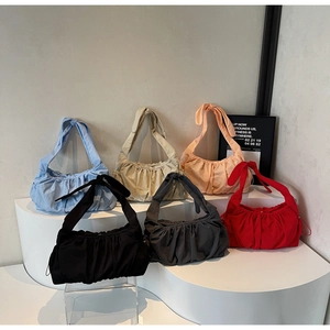 Close-up of pleated shoulder bags in six vibrant colors displayed on a podium