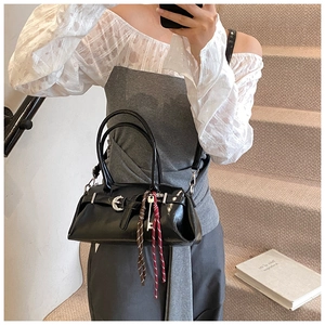 Détail du sac à bandoulière noir brillant avec boucle lune et pompons tissés