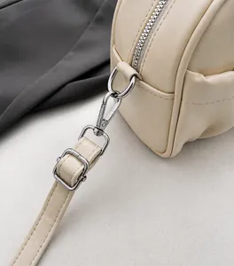 Close-up of premium silver hardware and neat stitching on a beige leather pillow bag