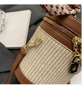 Close-up of barrel bag featuring woven texture, gold hardware, and silk scarf handle
