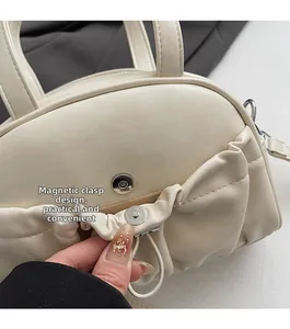Detail of the magnetic buckle closure on a beige pleated handbag with metal accents