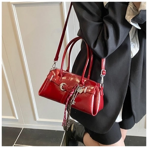 Fashionable red patent leather satchel bag with silver heart charm on model's side