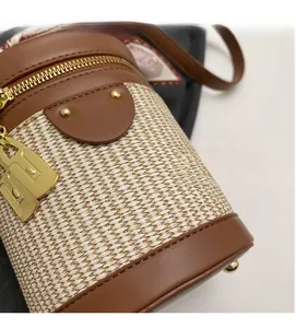 Close-up of woven cylinder bag with premium leather trim and gold metal lock detail
