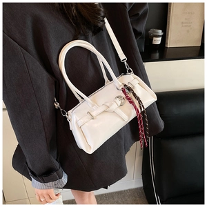 Detail of white leather boston bag with unique knot buckle and brown tassel charm