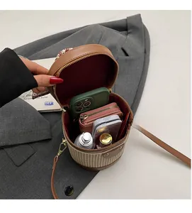 Interior capacity of cylinder crossbody bag showing phone and cosmetics inside