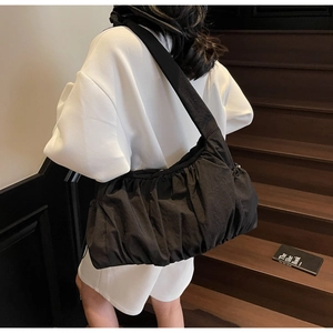 Black ruched nylon cloud bag shown from a side view for capacity and styling on person