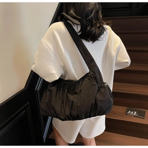 Modelo con un bolso de hombro tipo nube plisado negro con textura de nylon detallada