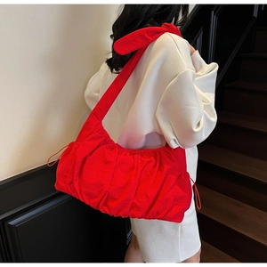 Detailed view of red pleated tote bag with drawstring texture on a female model