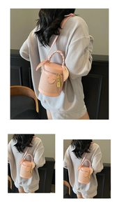 Detail of pink woven barrel bag with decorative silk scarf handle and metal lock