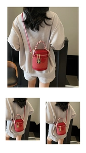 Detail view of red cylinder bucket bag with woven base and silk scarf wrapped handle