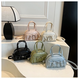 Various colors of pleated PU leather half-moon handbags displayed on white steps