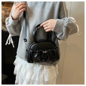 Detail of black pleated crossbody bag with silver hardware and adjustable strap