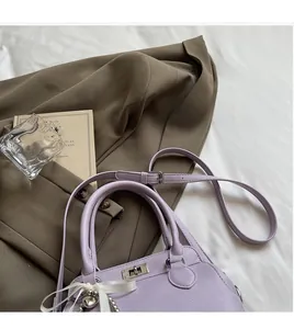 Detail of lavender milk box bag in pebble leather with silver clasp and silk bow