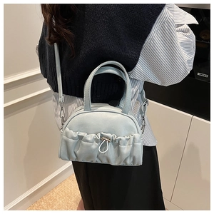Detail of light blue pleated pillow bag with metallic drawstring and detachable strap