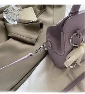 Close-up of light purple leather bag with silver hardware and pearl bow charm detail
