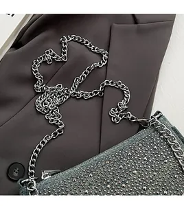 Macro shot of silver metal chain strap and studded denim fabric on a chic baguette bag