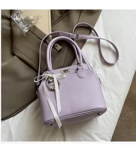 Detail of light purple lychee texture handbag with metal clasp and beaded bow charm
