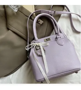 Detailed view of purple pebble leather handbag with silver heart charm and ribbon decor