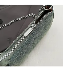 Close-up of smooth silver metal zipper and denim texture on vintage underarm bag