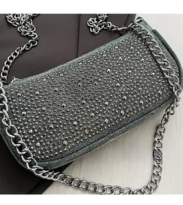 Detail of denim saddle bag with silver rhinestones and thick metal chain strap