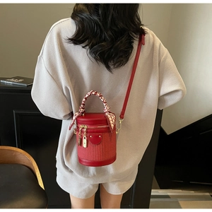 Detail of red cylindrical crossbody bag with woven texture and silk scarf handle