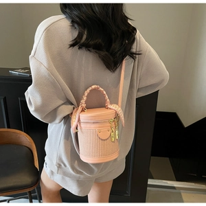 Pink cylindrical bucket bag with woven texture, scarf handle and gold lock detail
