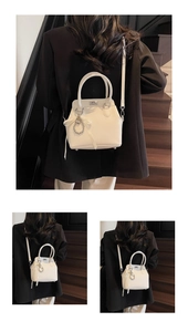 Close-up of minimalist cream mini Kelly bag with heart charm on a black blazer