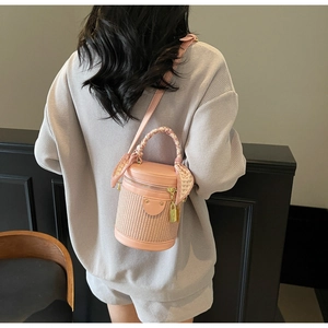 Detailed view of pink leather and beige woven cylinder bag with heart print silk scarf