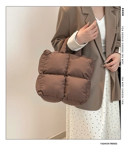Detail der dunkelbraunen Stepptasche mit Satin-Finish an einem Model in neutralem Outfit