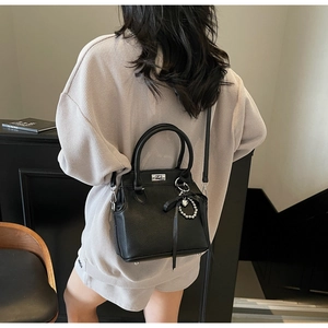 Detail of black lychee grain leather Kelly bag with silver hardware and heart charm