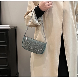 Detail view of blue denim saddle bag with silver studs and chain on beige coat
