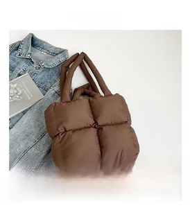 Detailansicht der braunen gesteppten Puffer-Tasche aus leichtem Nylon auf weißem Tisch