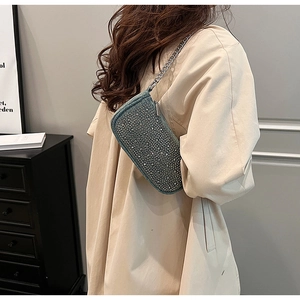 Detail of light blue denim underarm bag with silver rhinestones and metal chain strap