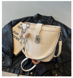 Dettaglio di una borsa a secchiello bianca con chiusura girevole e ciondolo di perle