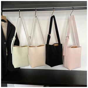 Detail von vier bunten Eimertaschen in Minzgrün, Beige, Schwarz und Rosa mit breiten Riemen